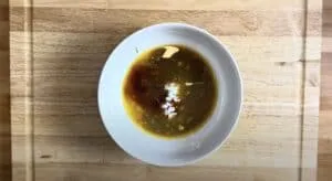 Bowl of soy sauce mix with garlic and spices on a wooden cutting board, perfect for Asian cooking recipes.